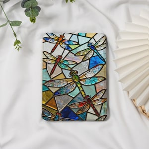 Puede incluir: Una funda rectangular con un diseño de vidriera que representa libélulas. Las libélulas son de varios colores, incluyendo rojo, naranja, azul y verde, sobre un fondo de formas geométricas multicolores.