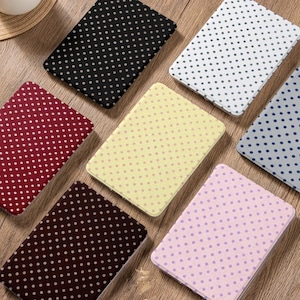 May include: A selection of rectangular fabric pieces in a variety of colours, each featuring a polka dot design. Colours include black, white, burgundy, yellow, brown, light purple, and blue. The polka dots are in contrasting colours to the fabric.