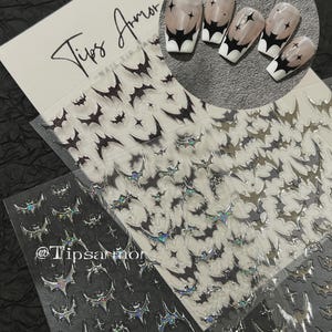 Peut inclure: Un ensemble d'autocollants pour ongles avec des silhouettes de chauves-souris noires et des étoiles, sur des feuilles transparentes avec le texte Tips Armor. Un encart circulaire montre cinq ongles avec une manucure française et des motifs de chauves-souris.