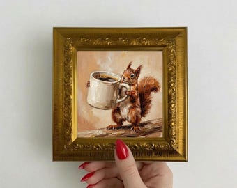 Può includere: Dipinto incorniciato raffigurante uno scoiattolo marrone che tiene in mano una grande tazza bianca di caffè. Lo scoiattolo è appollaiato su un ramo, con una coda soffice e pelliccia dettagliata. Il dipinto è in una cornice dorata ornata.