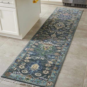 May include: A long, rectangular rug with a detailed floral pattern in shades of blue, green, and beige. The rug has a distressed look and a fringed edge, suitable for a kitchen or hallway.