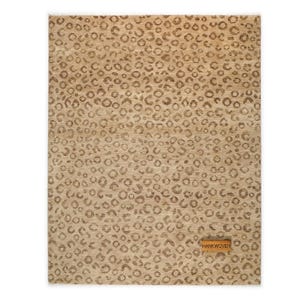 May include: A rectangular area rug with a tan background and a repeating pattern of brown leopard spots. A small, rectangular wooden tag with the text "HANKWOVEN" is attached to the rug.