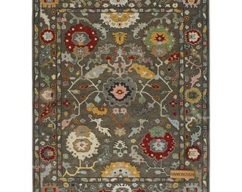 Puede incluir: Una alfombra rectangular con un intrincado diseño floral en tonos grises, rojos, amarillos y azules. La alfombra presenta un diseño de medallón central y un borde detallado. El texto "Hank Woven" es visible.