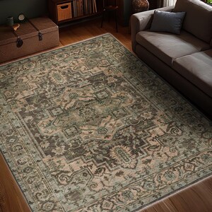 May include: An area rug with an intricate, traditional design in shades of brown, green, and beige. The rug features a detailed pattern with a border, placed on a hardwood floor. The rug is rectangular and covers a large area of the room.