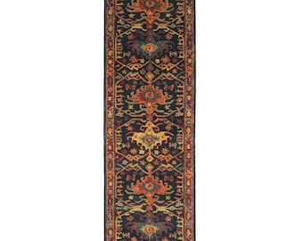 May include: A long, rectangular runner rug with a detailed, traditional design. The rug has a dark blue base with orange, yellow, and red floral and geometric patterns. The edges are bordered with a red and dark blue pattern.