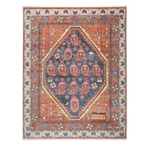 Pode incluir: Um tapete retangular, tecido à mão, com um design central em forma de diamante em azul marinho, apresentando motivos paisley em vermelho, rosa e amarelo. O tapete tem uma borda laranja com padrões florais e o texto "HANKWOVEN".