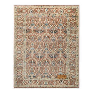 Pode incluir: Tapete retangular com um padrão simétrico detalhado em tons de ferrugem, bege e azul. O tapete apresenta um design ornamental de inspiração floral com uma borda. A etiqueta no canto diz "HANKWOVEN".