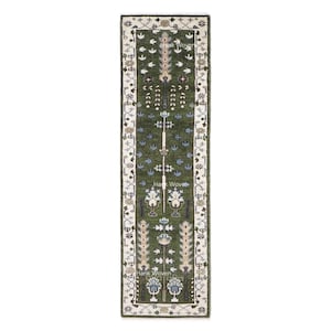 Könnte beinhalten: Ein rechteckiger, grüner Läufer mit einem komplizierten Blumenmuster. Der Teppich hat ein zentrales Feld in Dunkelgrün mit cremefarbenen und blauen Blumenmotiven. Der Rand ist cremefarben mit einem sich wiederholenden geometrischen Design. Der Text "Hank Woven" ist sichtbar.