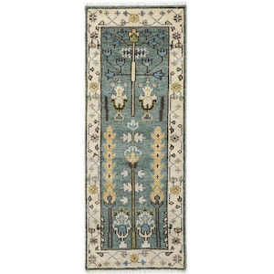May include: A rectangular, teal-colored rug with a cream-colored border. The rug features a central design of stylized floral and geometric patterns in shades of blue, yellow, and brown. The rug's dimensions are approximately 2 x 4 feet.