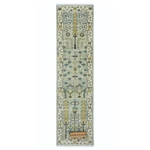Peut inclure: Un tapis rectangulaire et étroit avec un motif floral détaillé dans des tons de bleu, jaune et crème. Le tapis présente un motif central avec des motifs floraux symétriques et une bordure avec des motifs complexes. Le tapis a une frange aux deux extrémités et une étiquette "HANKWOVEN".