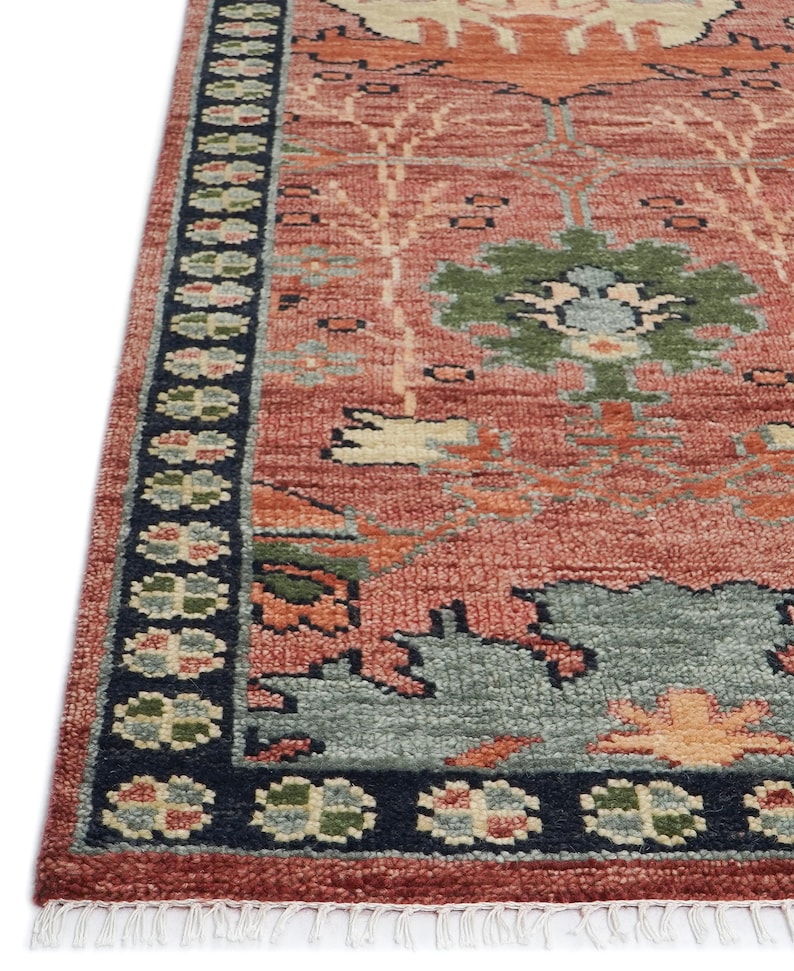Puede incluir: Una secci&oacute;n de una alfombra estampada en rojo y azul. La alfombra presenta un dise&ntilde;o central con motivos florales verdes, azules y naranjas. Un borde azul oscuro con patrones florales repetidos enmarca el borde. La alfombra tiene una apariencia texturizada.