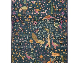 May include: A rectangular, dark teal rug with a detailed pattern of birds, trees, and floral elements in shades of orange, pink, and green. The rug has a border and a label that reads "HANKWOVEN".