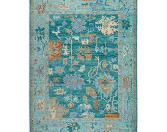 May include: A rectangular teal rug with an intricate floral pattern in shades of orange, blue, and beige. The rug has a border in a lighter teal shade, and the text "HANKWOVEN" is visible on the lower right corner.