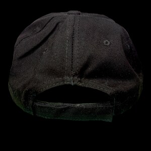 May include: A black baseball cap with a curved peak and an adjustable strap. The cap is made from a sturdy material and has a structured crown. The back of the cap has an adjustable strap for a comfortable fit.