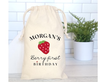 May include: A white cotton drawstring bag with a red strawberry and the text "MORGAN'S Berry first BIRTHDAY" printed on it.