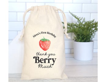 May include: A white cotton drawstring bag with a red and green strawberry illustration and the text "Alexa's First Birthday thank you Berry Much".