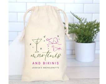 May include: A white cotton drawstring bag with a green and pink design of a martini glass and a bikini. The text "martinis and bikinis" is printed in green and pink. The text "Jessica's Bachelorette" is printed in black below the design.