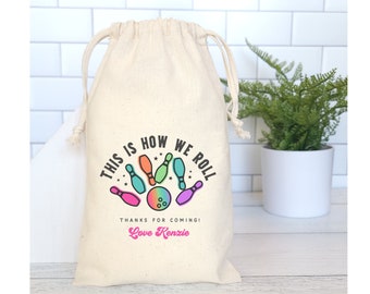 May include: A white cotton drawstring bag with a colorful bowling-themed design. The bag has the text "This is how we roll" and "Thanks for coming! Love Kenzie".