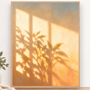 Könnte beinhalten: Ein rechteckiger Wandkunstdruck in einem hellen Holzrahmen mit einer gemalten Szene aus warmem goldenem Sonnenlicht, das lange Schatten von Pflanzenblättern und Fensterscheiben auf eine strukturierte Wand mit blauem Himmel wirft.