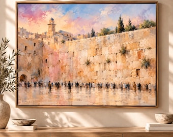 May include: A framed oil painting depicting the Western Wall in Jerusalem with a large crowd of people standing before the stone structure. The sky is filled with soft pink and blue clouds, and the scene is rendered in warm, earthy tones.