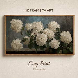 May include: A framed print depicting white hydrangea flowers against a muted blue backdrop. The artwork is in a wooden frame and includes the text "4K FRAME TV ART" and "Cozy Print Downloads".