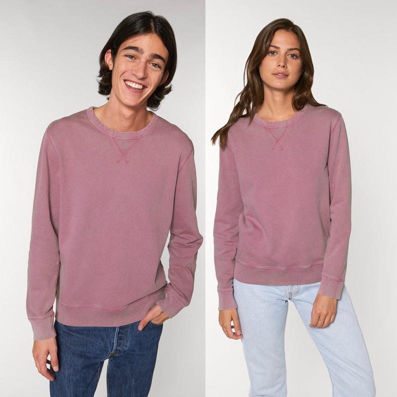 Puede incluir: Dos personas con sudaderas color malva a juego con cuello redondo. Las sudaderas tienen mangas largas y un dise&ntilde;o cl&aacute;sico. La persona de la izquierda lleva vaqueros azules. La persona de la derecha lleva vaqueros azul claro. Las sudaderas tienen un cuello cosido.