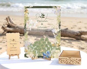 Peut inclure: Un ensemble de panneaux de mariage en bois, avec une plage en arrière-plan. L'ensemble comprend un grand panneau transparent avec des motifs floraux, un petit panneau sur chevalet, une boîte en bois et une alternative au livre d'or en forme de cœur. Les panneaux affichent les noms "Darwin & Louisa" et la date "2025.11.27".