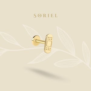 Può includere: Un orecchino a lobo con retro piatto in tonalità oro, caratterizzato da un design a cerotto rettangolare con un quadrato centrale e piccole perforazioni circolari alle estremità. Il marchio SORIEL è stampato sopra il gioiello.