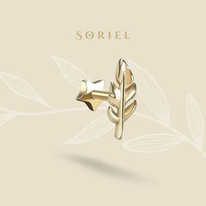 May include: A gold-colored earring with a leaf design and a star-shaped backing. The earring is a stud style and is set against a light beige background with the brand name "SORIEL" at the top.