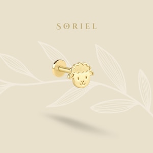 May include: A gold-colored stud earring featuring a sheep face design. The earring has a flat back and a post for insertion. The brand name "SORIEL" is displayed in the upper center of the image.