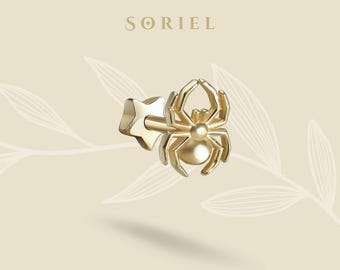 May include: A gold-colored stud earring featuring a spider design. The earring has a star-shaped backing and a detailed spider with eight legs and a rounded body. The word "SORIEL" is printed at the top of the image.