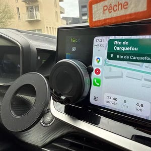 Könnte beinhalten: Schwarze Autotelefonhalterung mit kreisförmigem Magneten und Bildschirm mit Navigations-App. Der Bildschirm zeigt 16°C und den Text "Rte de Carquefou". Ein orangefarbener Lufterfrischer mit dem Wort "Pêche" ist sichtbar.