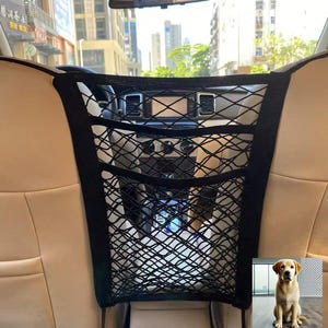 May include: Black mesh cargo net for the backseat of a car. The net has multiple compartments and is secured to the headrests. A golden retriever dog is pictured in the bottom right corner.