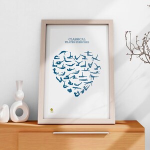 May include: A white framed print with the text "Classical Pilates Exercises" and a blue silhouette of a heart made up of various Pilates exercises.
