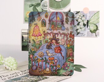 May include: A whimsical illustration of a witch in bed with cats and mushrooms. The artwork features a cozy bedroom scene with a blue bedspread, a window, and various decorative elements. The color palette includes pink, green, and blue.