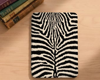 May include: A rectangular electronic e-reader device featuring a high-contrast black and white zebra stripe pattern across its entire front surface. The device is positioned vertically, displaying a bold, repeating animal print design with organic lines.