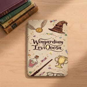 May include: A rectangular e-reader cover with a cream background featuring illustrations of a golden snitch, a brown sorting hat, a potion bottle labeled Felix Felicis, a wand, a golden cup, and glasses, with the text Wingardium LeviOoosa.