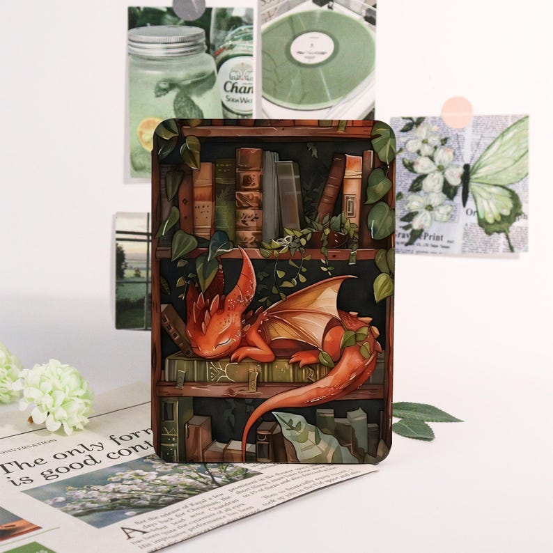 May include: A decorative rectangular item featuring a detailed illustration of a red dragon resting on a bookshelf filled with books. The dragon has orange wings and is surrounded by green vines. The background includes other decorative elements.