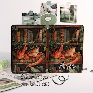 May include: Two Kindle cases with a fantasy design. Each case features a red dragon resting on a bookshelf filled with books and greenery. The text "Customize your own kindle case" is at the bottom.