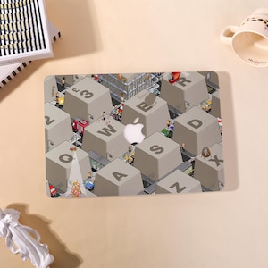 May include: A laptop skin featuring a cityscape design integrated into a keyboard layout. The keys are large, gray, and labeled with letters and numbers. The Apple logo is visible. The design includes miniature figures and vehicles.