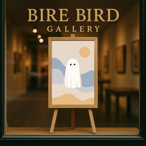May include: A wooden framed art print on a small easel, displaying a minimalist ghost illustration. The artwork has a beige background with blue and tan landscape elements and a yellow sun. The text "BIRE BIRD GALLERY" is above the artwork.