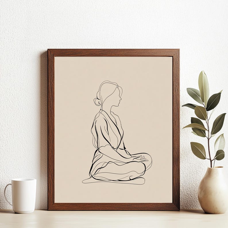 May include: A framed line art print featuring a minimalist illustration of a person in a seated meditation pose. The artwork is rendered in black lines on a beige background, encased in a brown wooden frame. The artwork evokes a sense of calm and serenity.