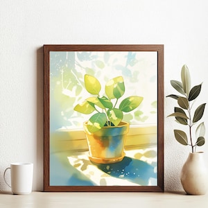 May include: A framed watercolor painting of a potted plant with green and yellow leaves in a brown pot. The plant is sitting on a windowsill with sunlight streaming in.