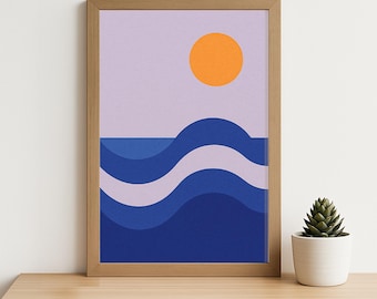 May include: A framed art print featuring an abstract ocean scene. The artwork depicts an orange sun against a lavender sky, with layered blue waves. The print is in a natural wood frame and sits on a wooden surface.