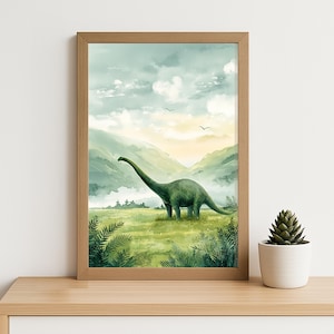 Peut inclure: Impression aquarelle encadrée d'un Brachiosaure vert dans un champ herbeux. Le fond présente des collines verdoyantes, un ciel nuageux et un coucher de soleil. Le cadre est en bois brun clair. Un petit pot de succulente est posé sur une surface en bois.