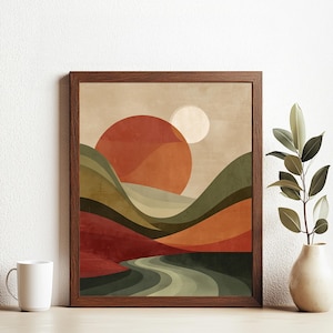 May include: Abstract landscape art print in a brown wooden frame. The artwork depicts a sunset over rolling hills, with a river winding through the scene. The colour palette includes shades of orange, green, and brown.