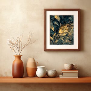 May include: A framed art print featuring a jaguar peering through lush green and yellow foliage. The artwork is set in a dark brown wooden frame with a white mat. The print is displayed on a wooden shelf with decorative vases and books.