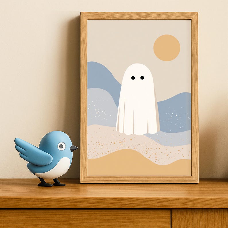 May include: A framed art print with a minimalist ghost illustration against a beige backdrop, blue waves, and a yellow sun. A blue bird ornament is placed on a wooden surface in front of the artwork.