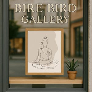 May include: A framed line art print of a person in a yoga pose, displayed in a shop window. The print is in a light wood frame and features a minimalist design. The window also displays the text "BIRE BIRD GALLERY". A small potted plant sits on the window ledge.