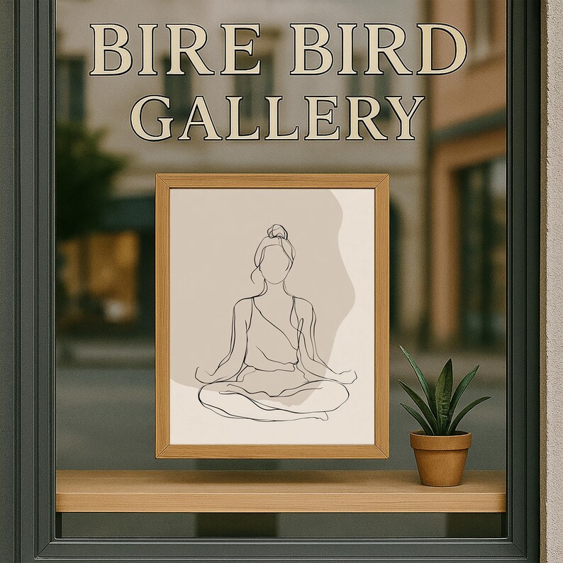 May include: A framed line art print of a person in a yoga pose, displayed in a shop window. The print is in a light wood frame and features a minimalist design. The window also displays the text "BIRE BIRD GALLERY". A small potted plant sits on the window ledge.